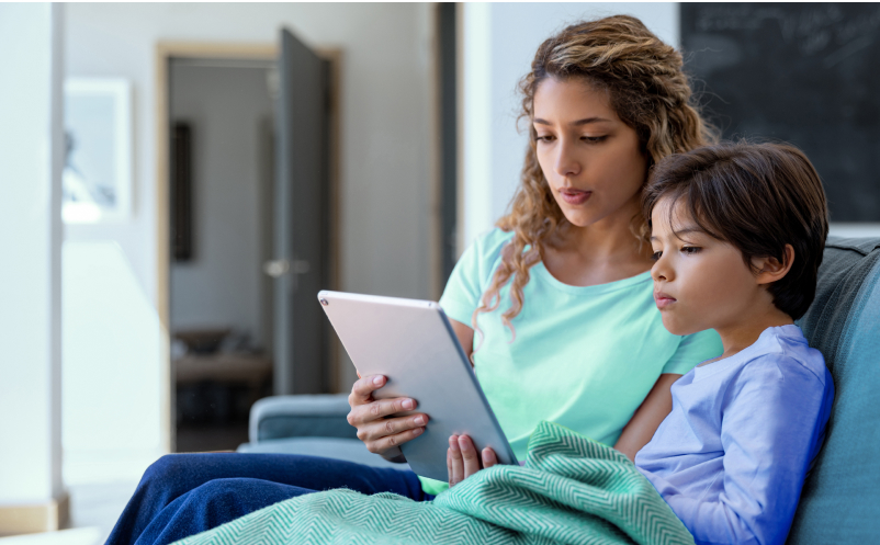 woman and child sitting next to each other holding a tablet device